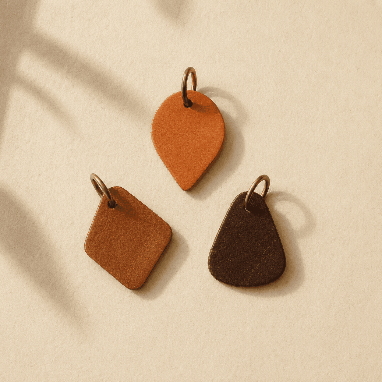 Three small leather charms in tan, brown and black on brass rings