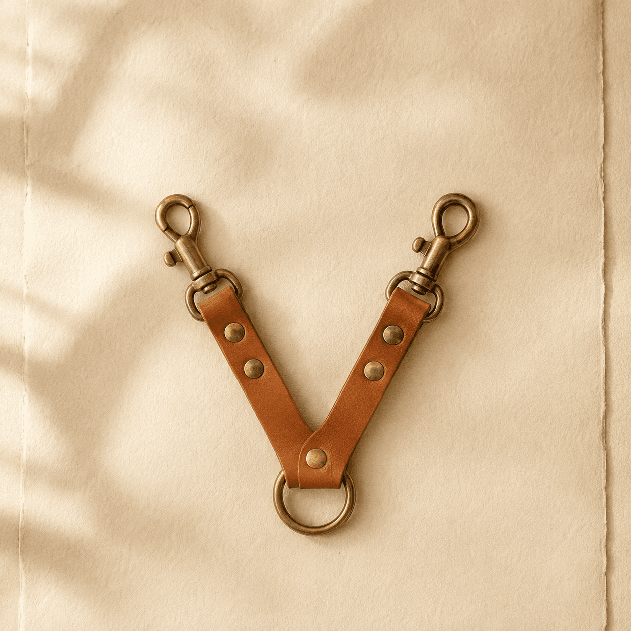 A Y-shaped leather coupler with two brass snaps meeting at a central ring