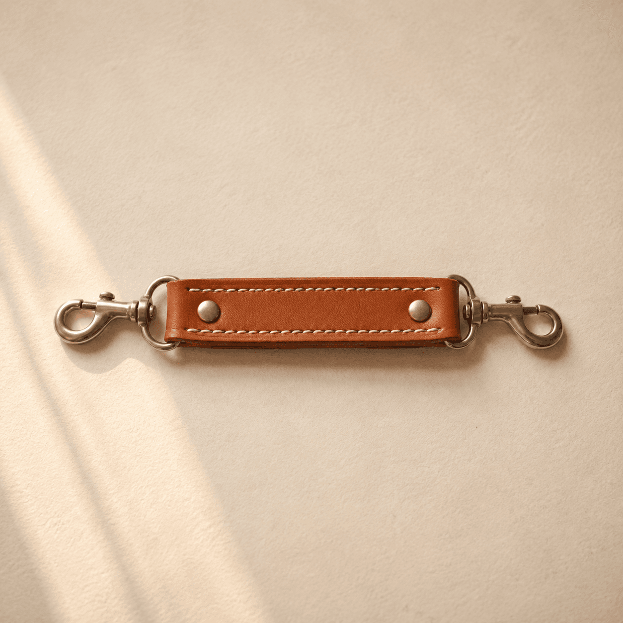 A short folded leather grab handle with two stainless snap hooks