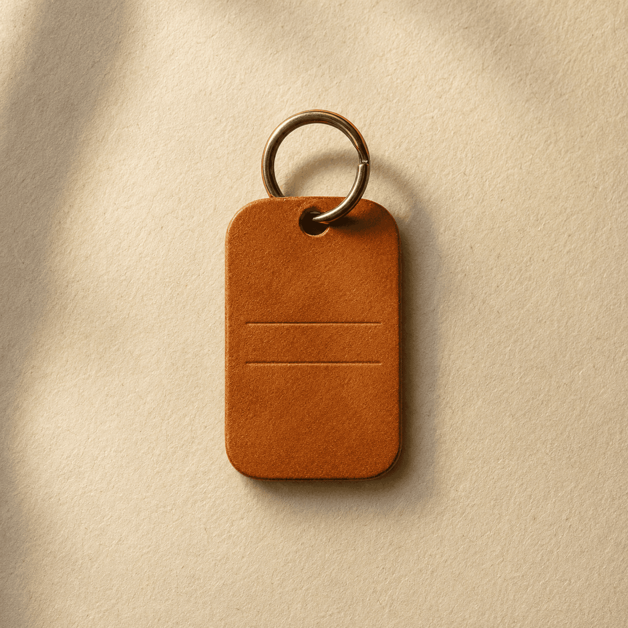 A small rectangular leather dog tag blind-stamped with two lines of text, on a brass ring