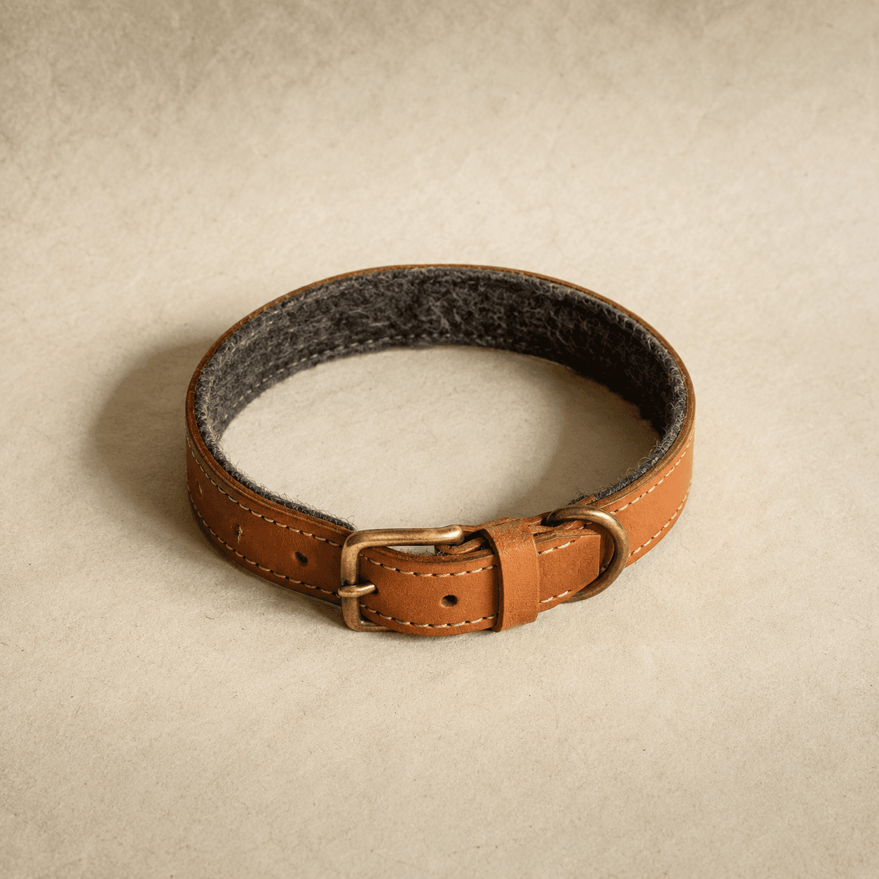 A tan leather collar with a grey wool felt lining visible along the inner edge