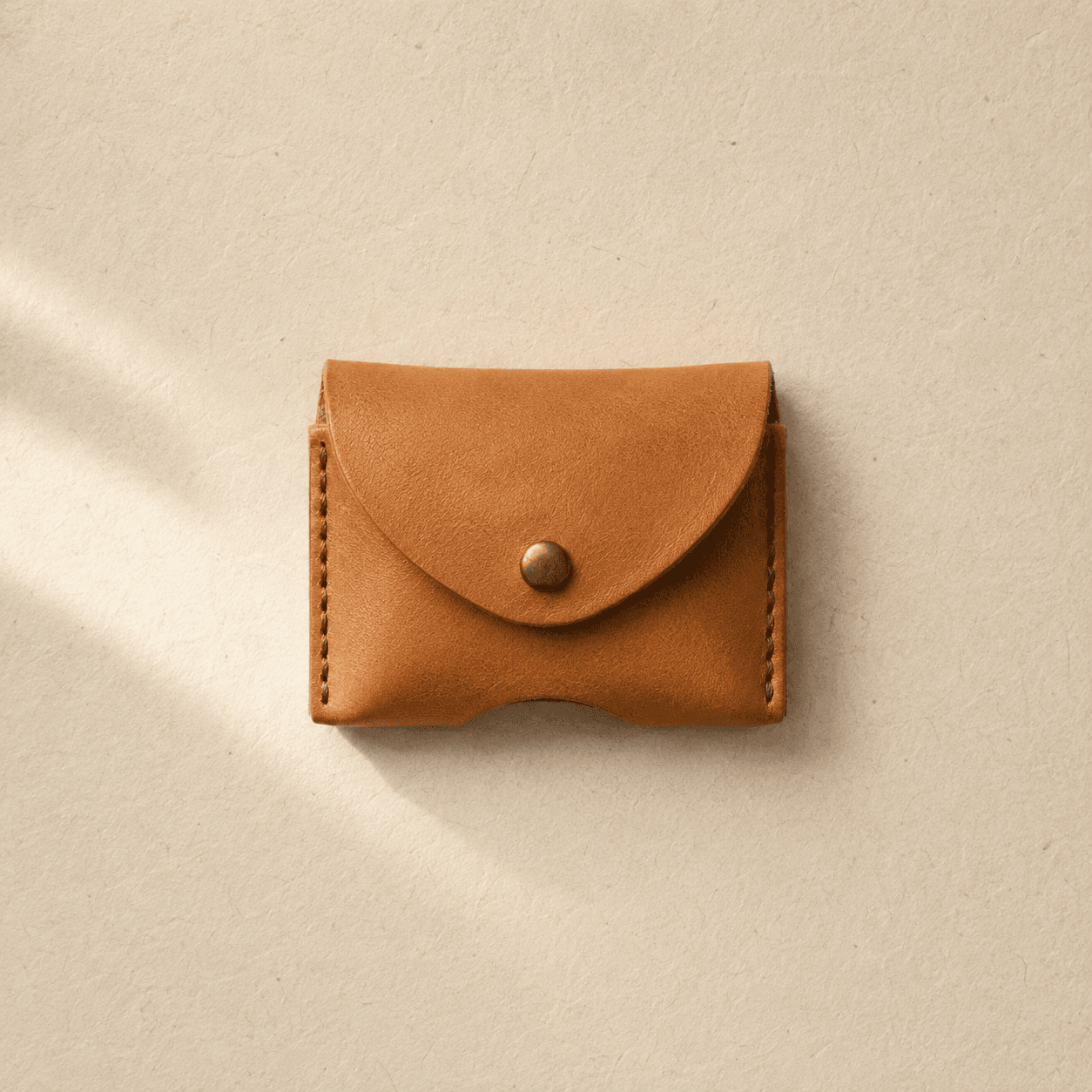 A small tan leather sleeve with a press stud, sized to wrap around dog tags