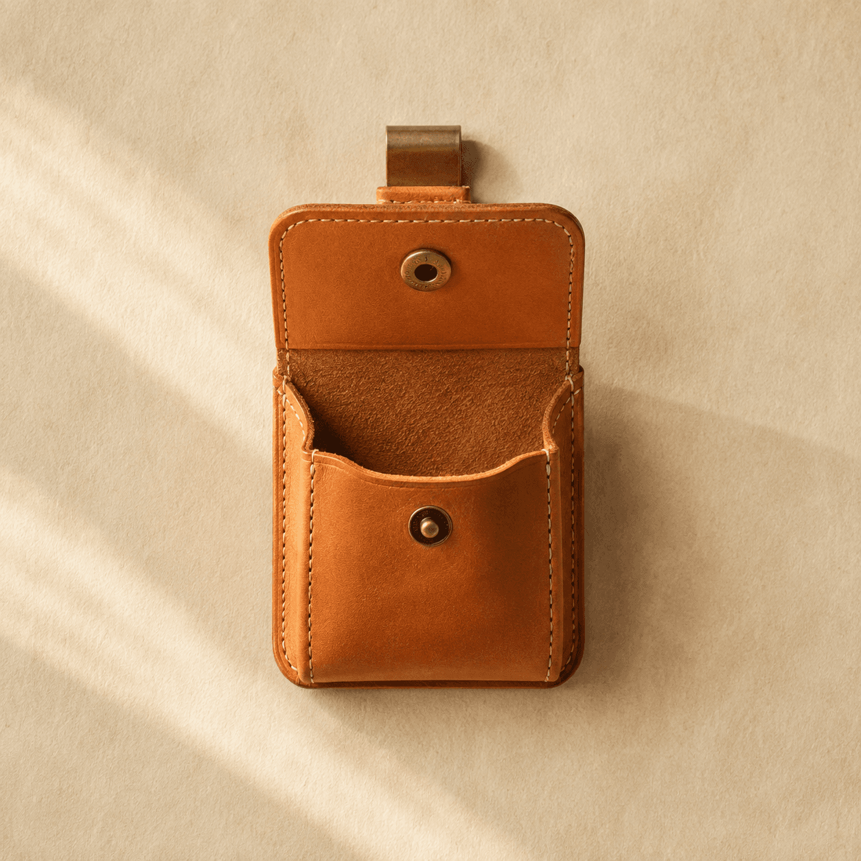 A small open-top tan leather pouch with a brass belt clip and press stud