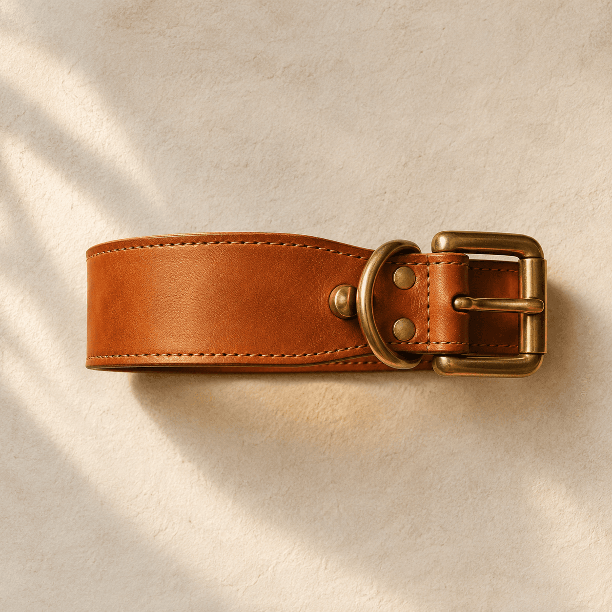A 40 mm wide tan leather collar with a brass roller buckle, tapered towards the buckle end